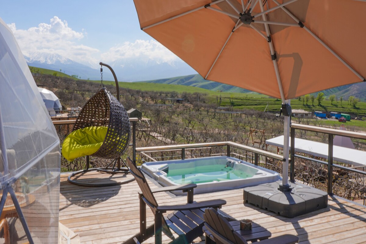 Une terrasse en bois avec un jacuzzi, des sièges d’extérieur et un grand parasol.