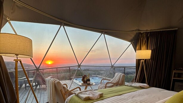 A bedroom with a large bed, a view of the sunset, and a hot tub outside. - EcoHouse Glamping by ART HOTEL (Bishkek)
