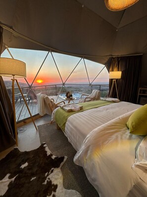 Ein Schlafzimmer mit einem großen Bett, Blick auf den Sonnenuntergang und einer Außenwhirlpool.