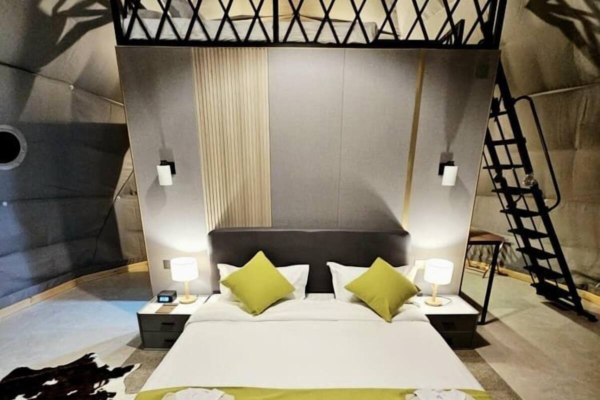 Un dormitorio con una cama litera, una mesita de noche con lámpara y una alfombra de cuero de vaca.