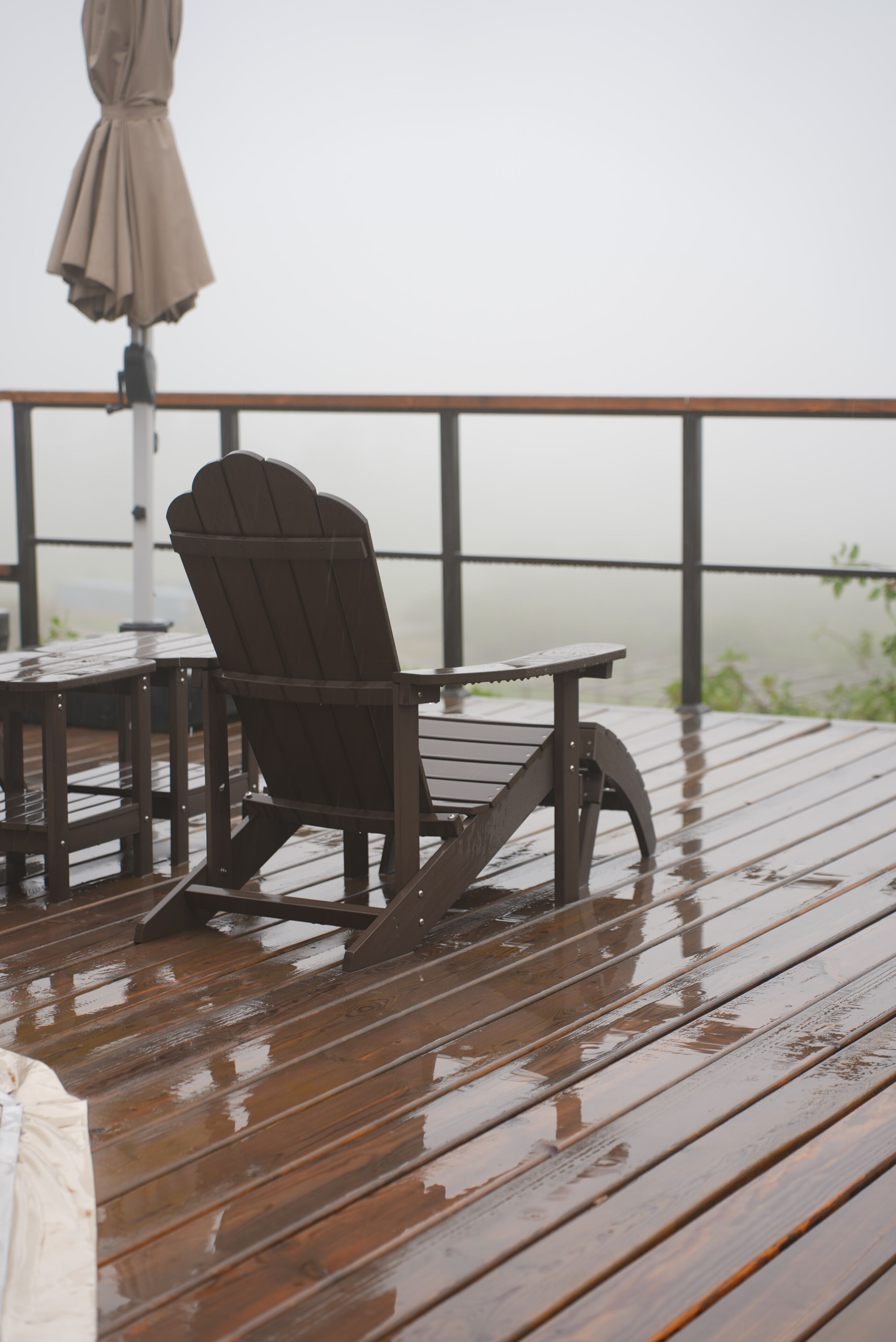 Une terrasse en bois avec une chaise et une table, une rambarde et une vue sur l’eau.