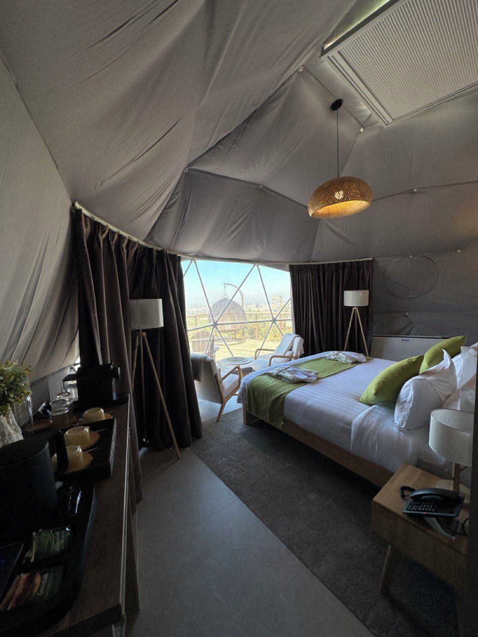 A tent-style room with a bed, bedside tables, a desk, and a chair.