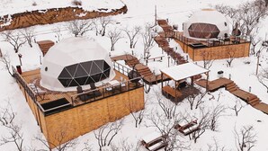 Two geodesic dome structures with wooden decks and outdoor seating areas, surrounded by snow-covered terrain and sparse vegetation. - EcoHouse Glamping by ART HOTEL (Bishkek)
