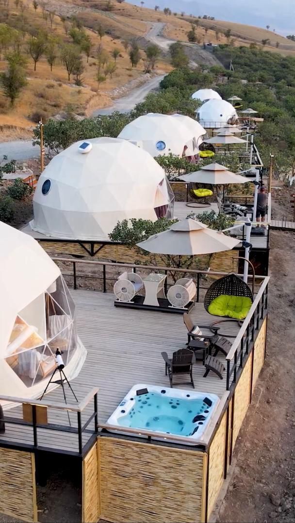 A series of geodesic dome structures with outdoor seating and a hot tub.