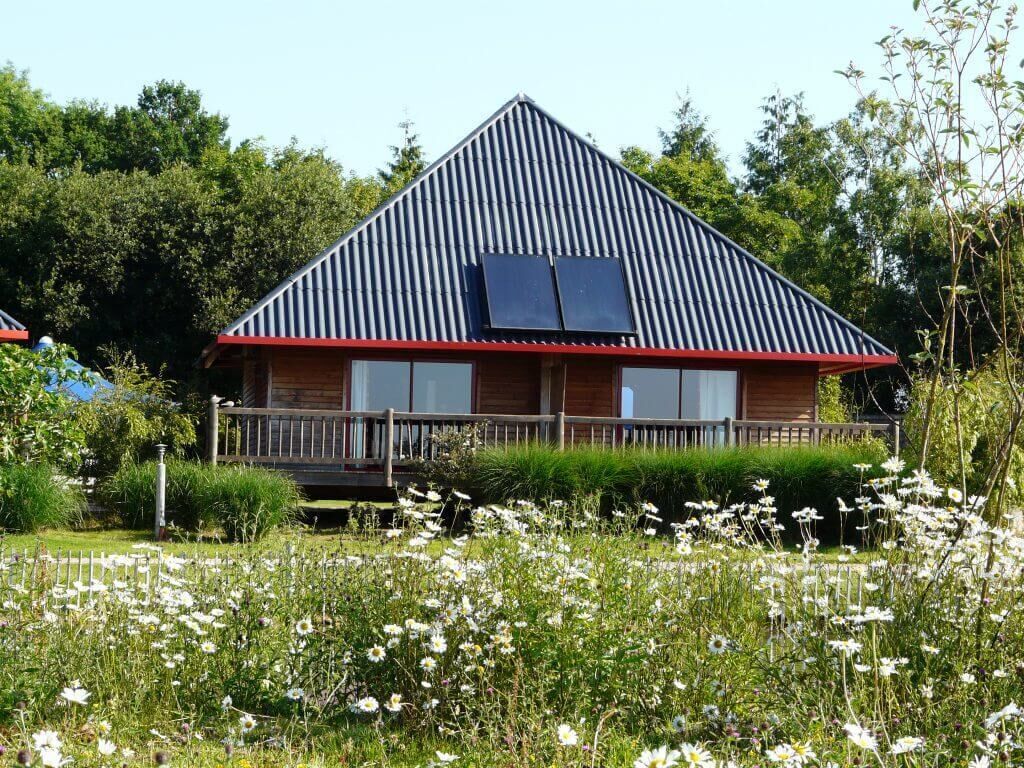 A house with a sloped roof, a balcony, and solar panels.