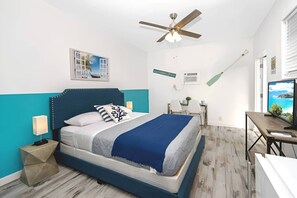 A bedroom with a bed, a ceiling fan, a desk, and a TV.
