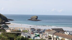 A coastal town with a beach, rocky outcrop, and buildings along the shore. - Lodge 83, Gwel an Mor (Redruth)