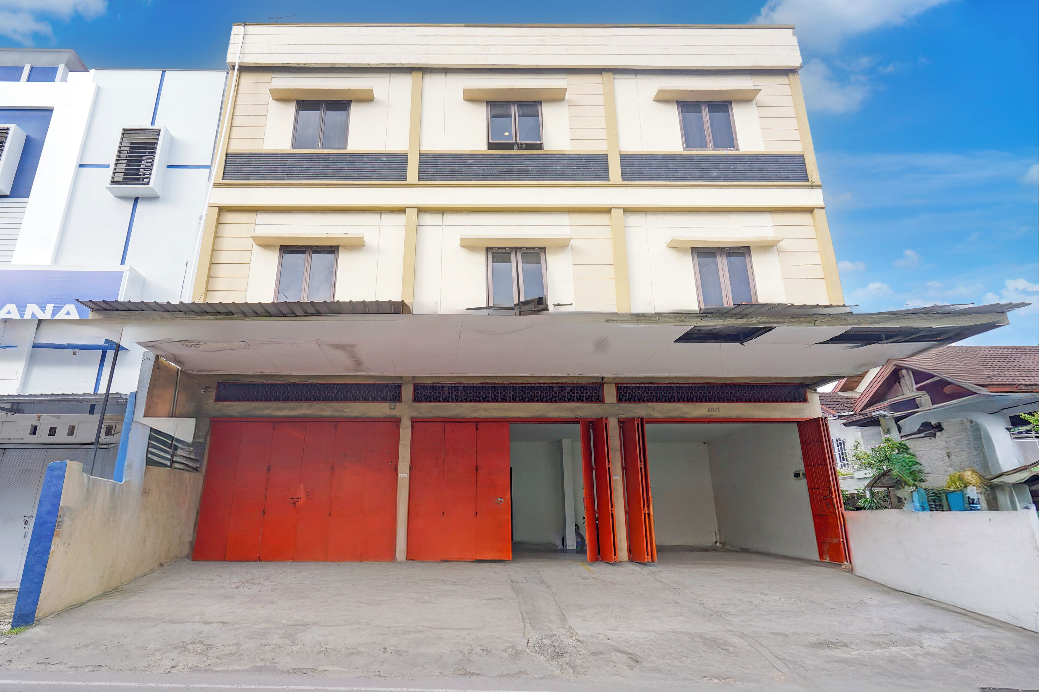 A multi-story building with a flat roof, large red garage doors, and a covered entrance.