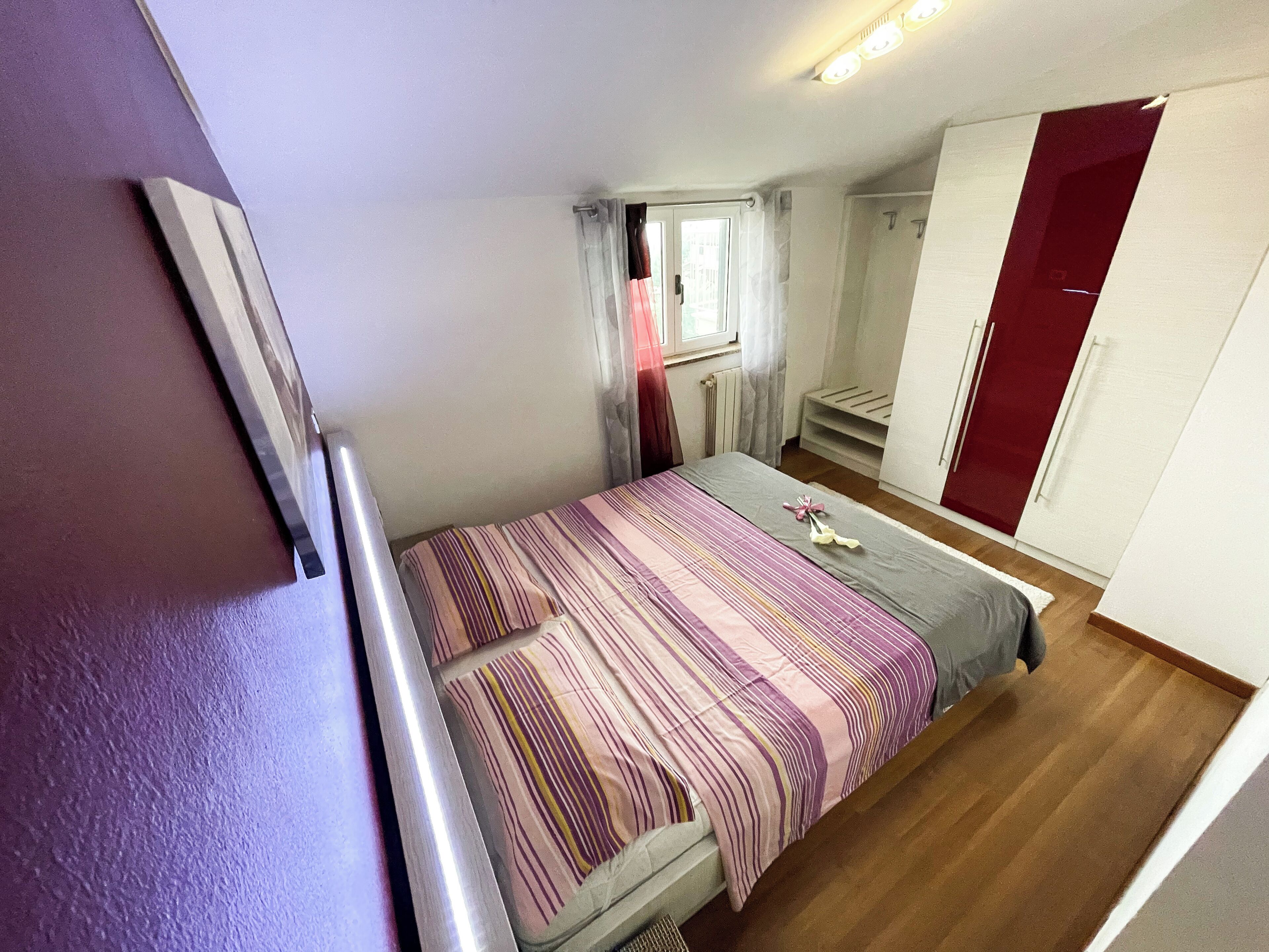 Un dormitorio pequeño y acogedor con cama, ventana con cortinas, armario y puerta.