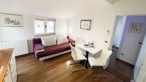 A compact living space with a red sofa, a small dining table with chairs, and a white radiator.