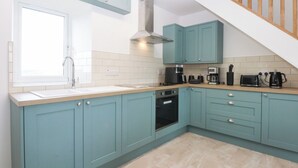 A kitchen with teal cabinets, a built-in oven, a coffee maker, and a toaster.