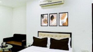 Habitación de hotel con cama, una silla y un equipo de aire acondicionado en la pared.