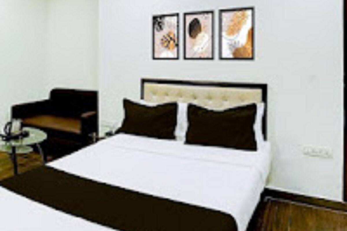 A hotel room with a bed, a chair, and an air conditioning unit on the wall.