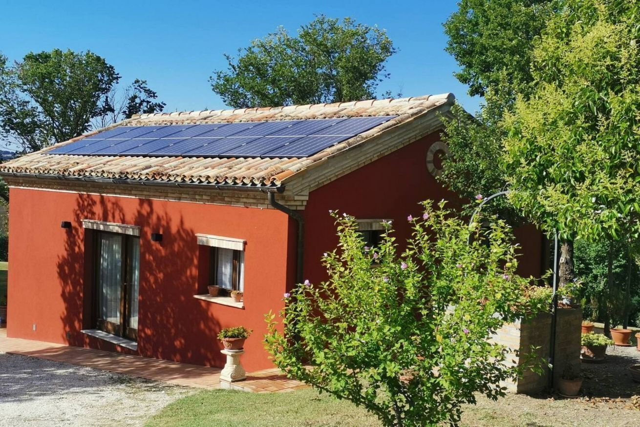 Un bâtiment à l’extérieur rouge, doté d’un toit en tuiles et équipé d’un ensemble de panneaux solaires.