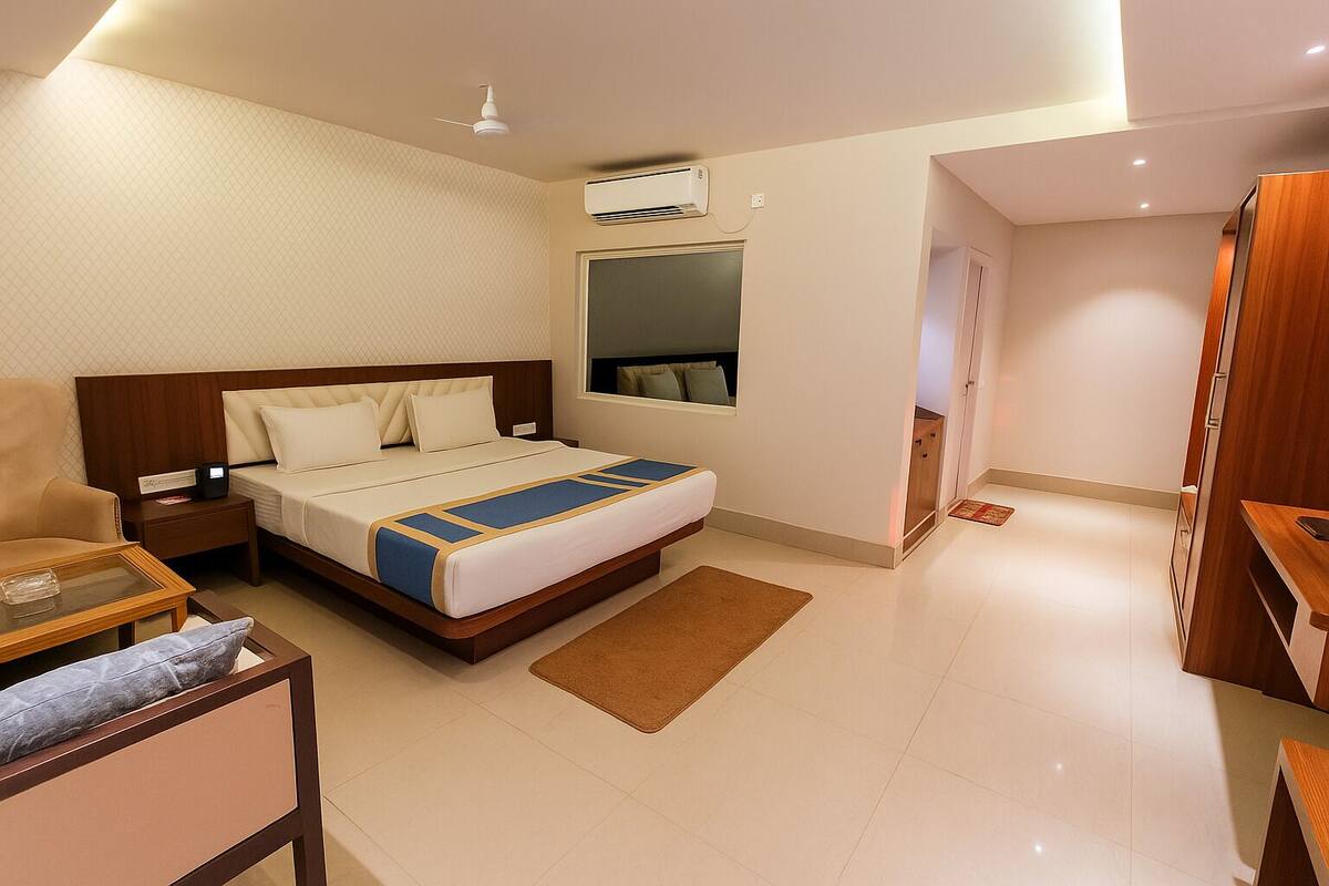 Una camera d'albergo moderna con un letto grande, un comodino, una sedia, una scrivania, un climatizzatore e un armadio.