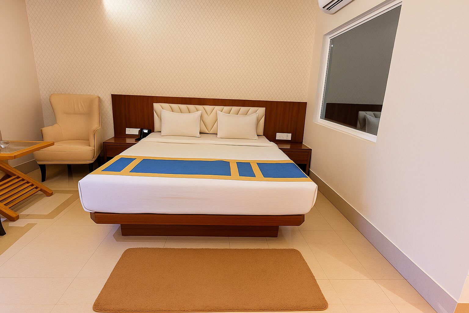 A hotel room with a bed, a chair, a nightstand, and a window.