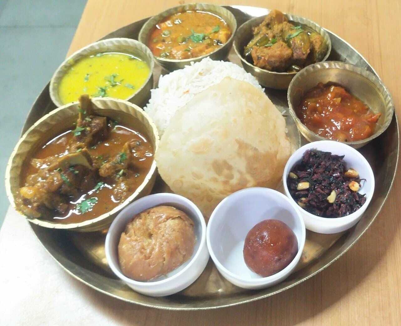 Comida tradicional india con arroz, curry y chutney sobre un plato de metal.