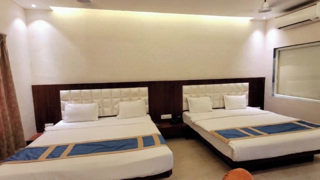 Een hotelkamer met twee bedden, een groot raam en een luchtverkoeler aan het plafond.