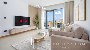 Ett modernt vardagsrum med en platt-TV, en soffa, ett soffbord och utsikt över Dubais skyline.