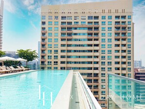 A high-rise building with a swimming pool and sun loungers. - LUX  The Vida Marina Residence (Dubai)