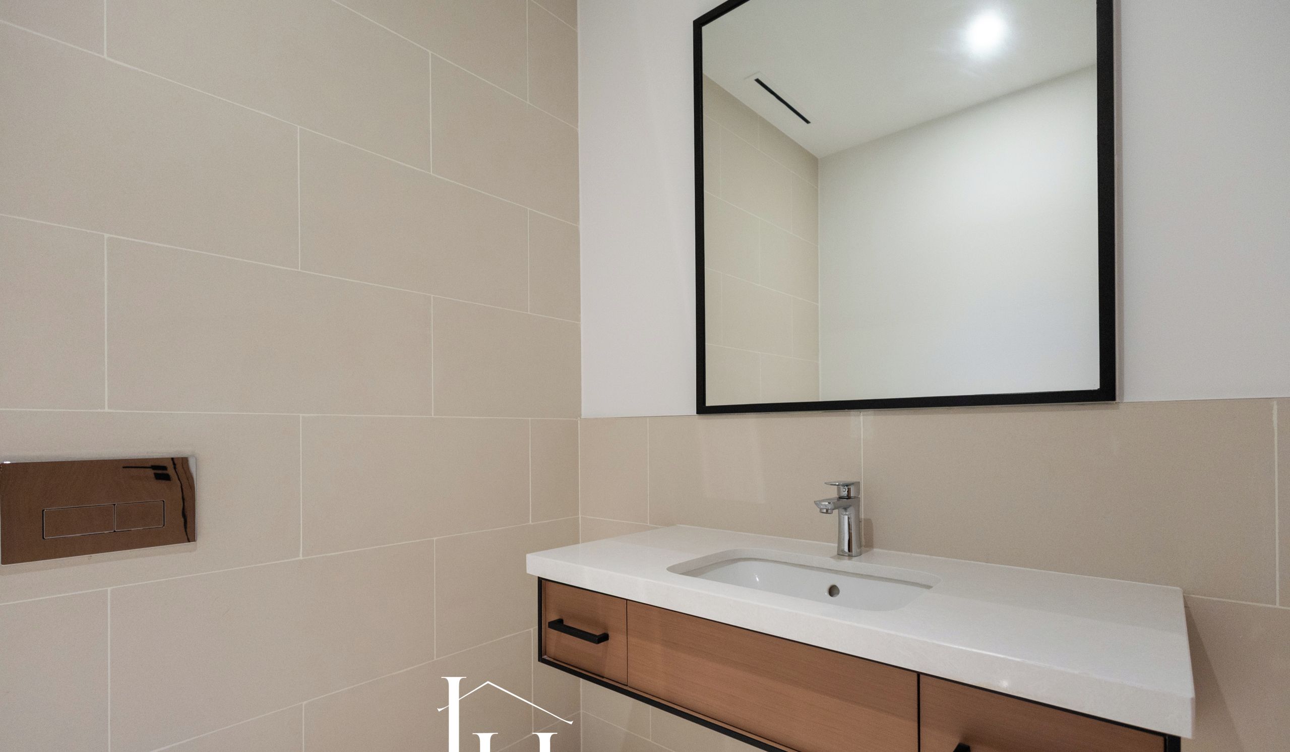 Un baño con lavamanos blanco, mueble de madera y un espejo grande.