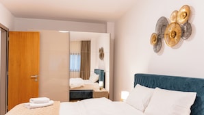 A hotel room with a bed, a wooden wardrobe, a mirror, and a wall art piece. - Garden side Emma accommodation in Monarh Tower (Timișoara)