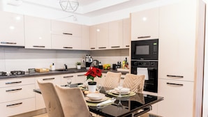 A modern kitchen with white cabinets, a black countertop, and a dining table set for two. - Garden side Emma accommodation in Monarh Tower (Timișoara)