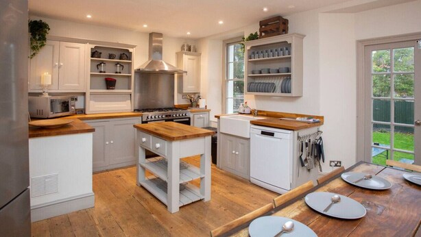 A modern kitchen with white cabinetry, a wooden countertop, a built-in stove, and a dishwasher.