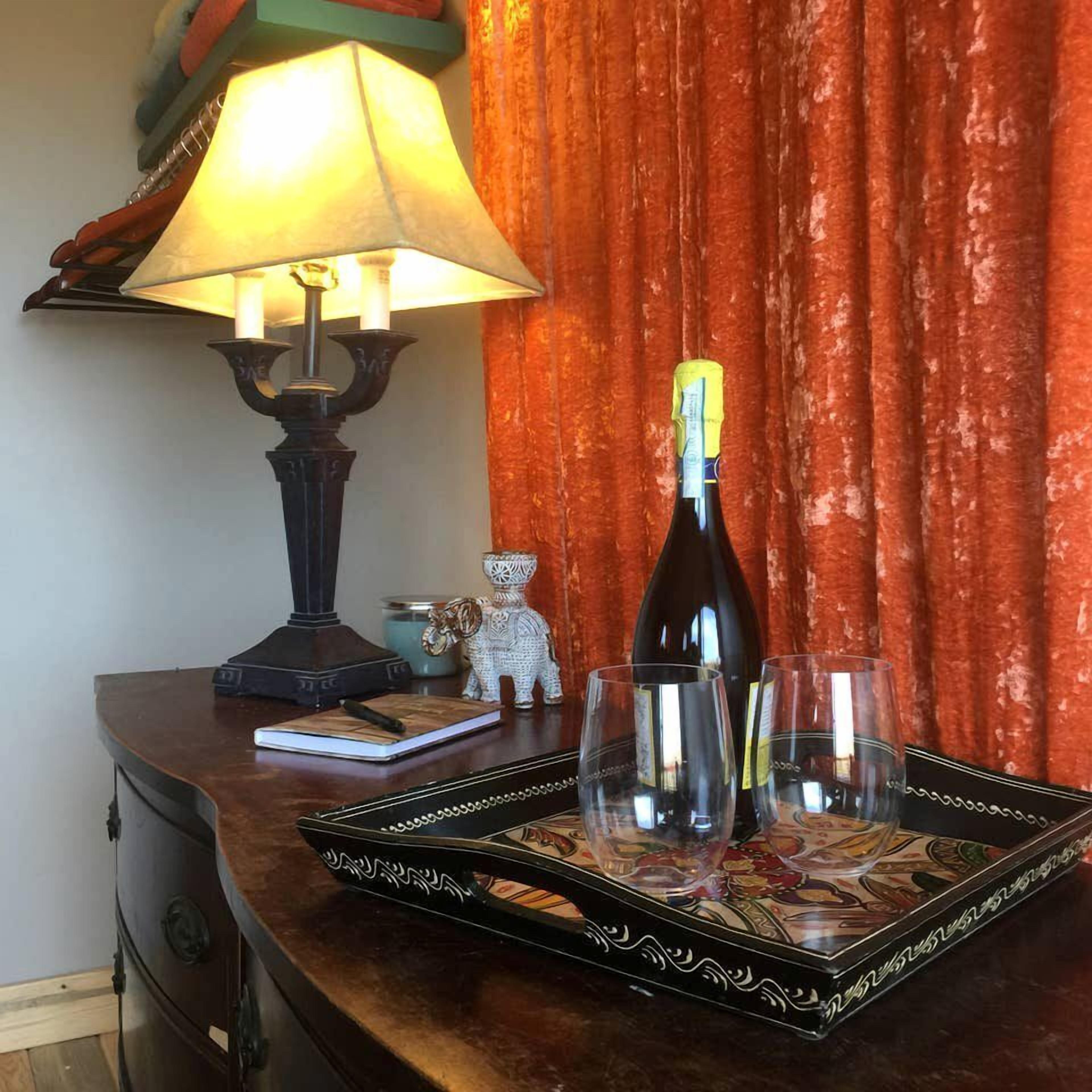 A bottle of wine on a tray, a lamp, and a small figurine on a wooden table.