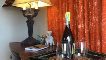 A bottle of wine on a tray, a lamp, and a small figurine on a wooden table.