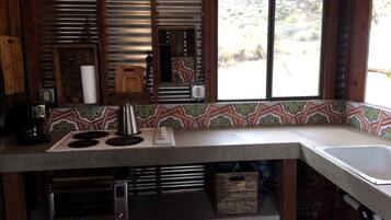 A kitchen with a built-in stove, a sink, and a window with a view of the outdoors.