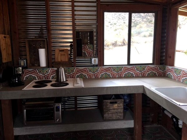 A kitchen with a built-in stove, a sink, and a window with a view of the outdoors.