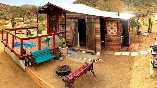 A rustic cabin with a deck, outdoor seating, and a swimming pool. - Romantic Yucca Valley Cabin with Hot Tub (Yucca Valley)