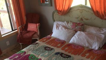 A bedroom with a bed, a chair, and a window with curtains.