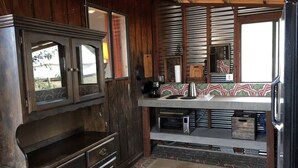 A rustic kitchen with wooden cabinets, a built-in oven, a coffee maker, and a microwave. - Romantic Yucca Valley Cabin with Hot Tub (Yucca Valley)