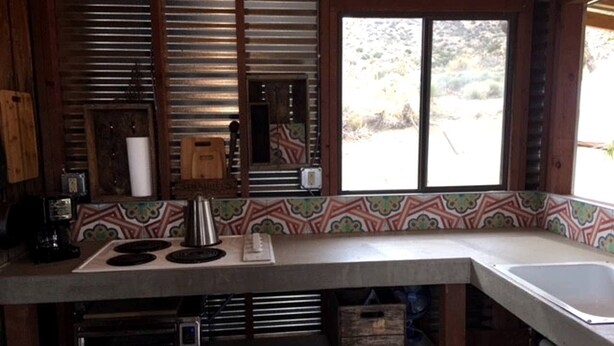 A kitchen with a built-in stove, a sink, and a window with a view of the outdoors. - Romantic Yucca Valley Cabin with Hot Tub (Yucca Valley)