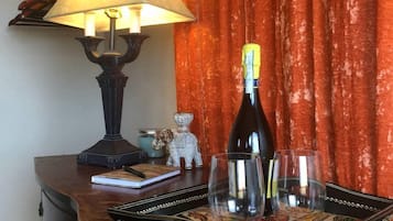Eine Weinflasche auf einem Tablett, eine Lampe und eine kleine Figur auf einem Holztisch.