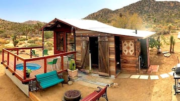 A rustic cabin with a deck, outdoor seating, and a swimming pool.