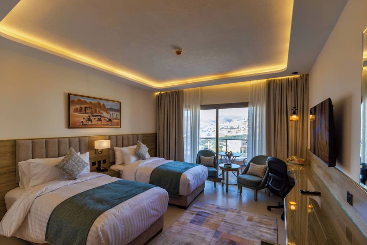 A hotel room with two beds, a desk, a chair, a TV, and a balcony with curtains.