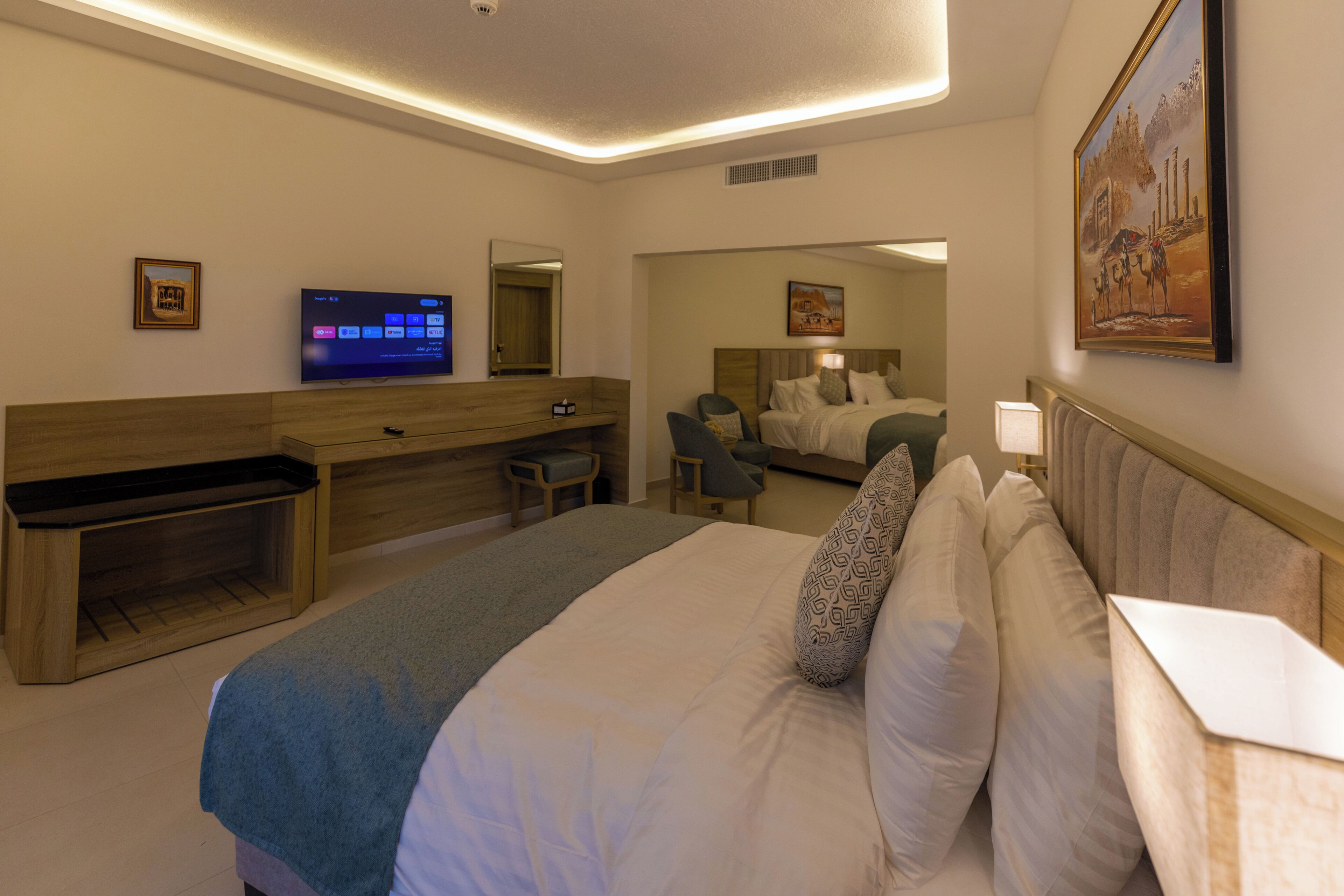 A hotel room with a large bed, a desk, a television, and a mirror.