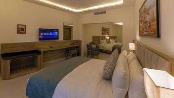 A hotel room with a large bed, a desk, a television, and a mirror.