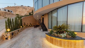 Ein modernes Hotel mit einer geschwungenen Fassade, einem Steinweg und einer Treppe zum Eingang.
