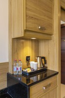 Una cocina con armarios de madera, una encimera, un hervidor, dos botellas de agua y una cafetera.