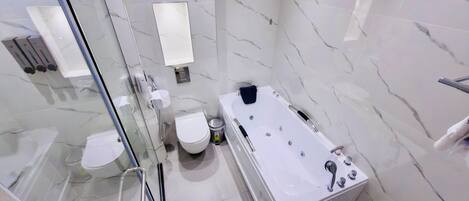 A modern bathroom with a glass shower enclosure, a toilet, a bathtub, and a hand dryer.