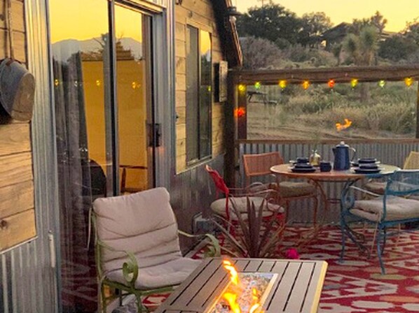Une terrasse dotée d’un foyer, de sièges et d’une table avec des chaises.