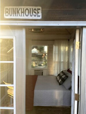 A bunkhouse with a bed, a window with a view, and a sign above the door.