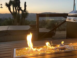 A fire feature with a view of the city at sunset.