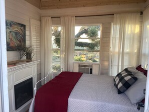 Une chambre à coucher avec un lit, une cheminée, une fenêtre avec des rideaux et une vue sur l’extérieur.