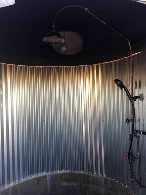 A bathroom with a shower, a ceiling-mounted light fixture, and a wall with vertical metal slats. - Unique Yucca Valley Rental Ideal for Romantic Getaways in California (Yucca Valley)