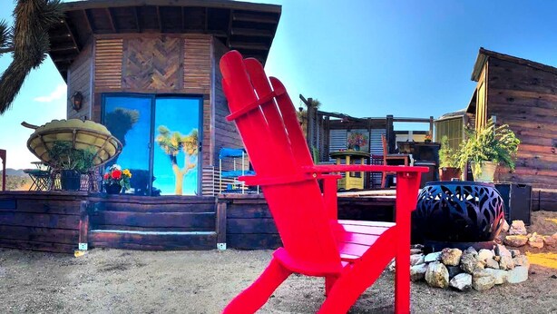 A red chair in front of a building with a wooden facade and a large window.
